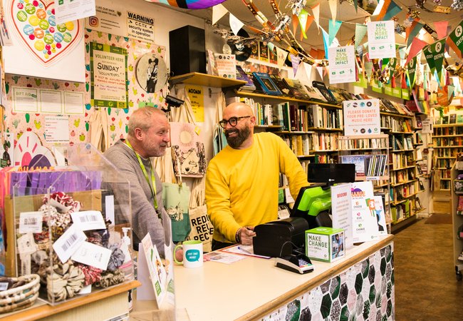 Shop Manager and Volunteer Smiling Behind colourful till