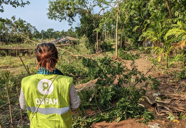 An Oxfam worker stands with their back to the camera.