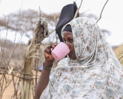 Abida drinks from a pink plastic cup.