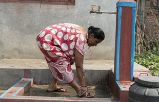 Rama washes at a tap built in her yard.