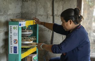 Sangita heats and shapes leaves into a plate using the machine provided by Oxfam and partner organisation, RDC.