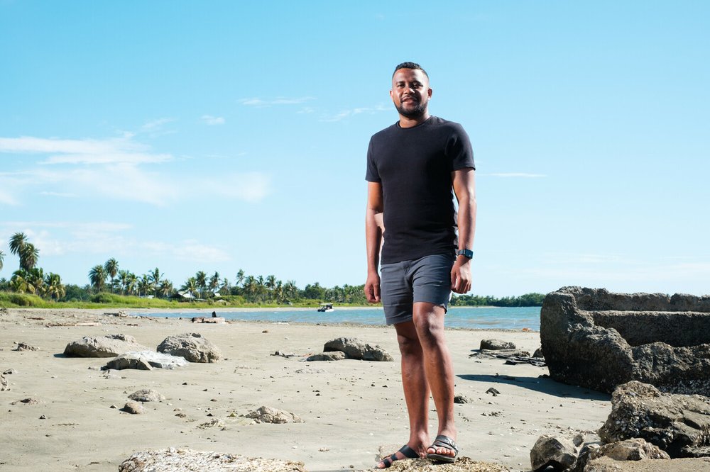 Climate activist Lavetanalagi Seru stands on a beach in his home country of Fiji.