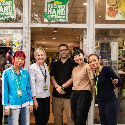 Group of smiling volunteers outside an Oxfam shop