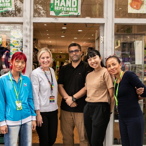 Group of smiling volunteers outside an Oxfam shop