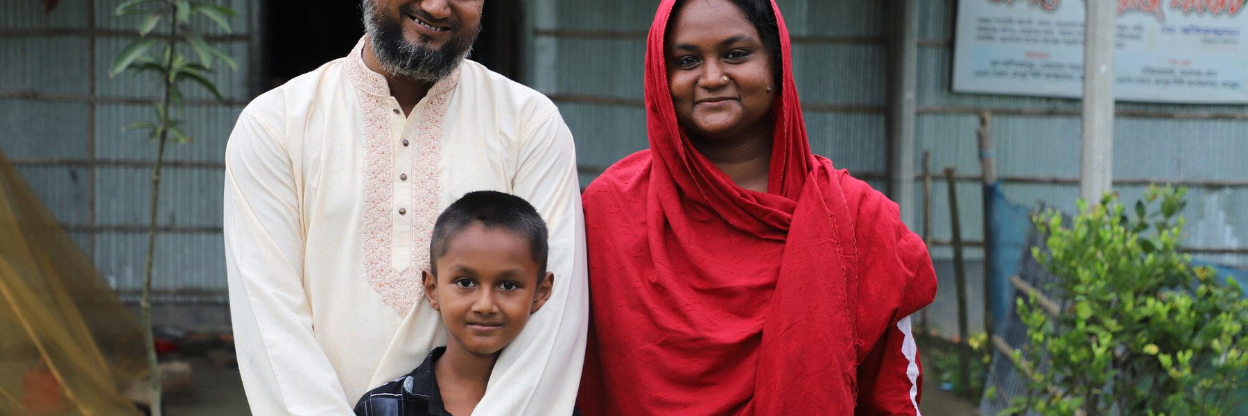 Nujhat (29) and husband Zakir (35) stand outside their rug-making business in Bangladesh with their son Talha.