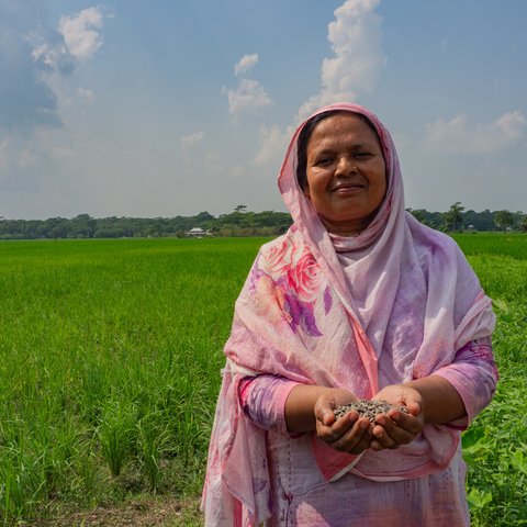 Dulu, a Bangladeshi woman in a pink hijab, smiles and looks at the camera.