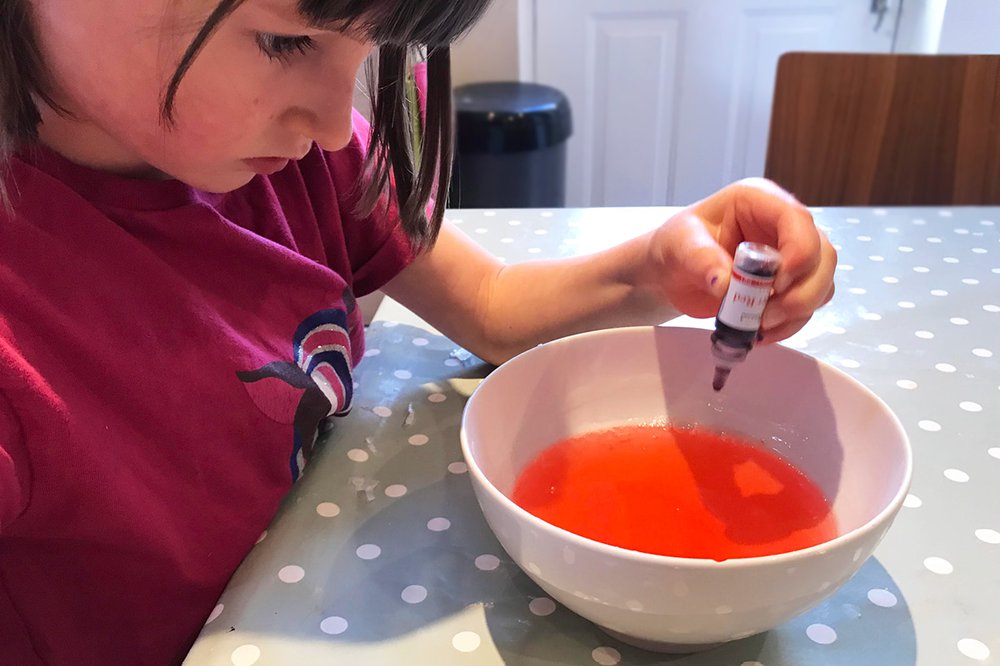 A girl uses a pippete to add colouring to glycerin