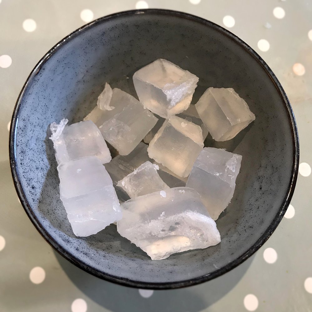 Squares of clear glycerin in an earthware bowl on a polkadot grey tablecloth