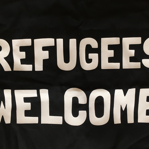 A close up of a tote bag that says refugees welcome