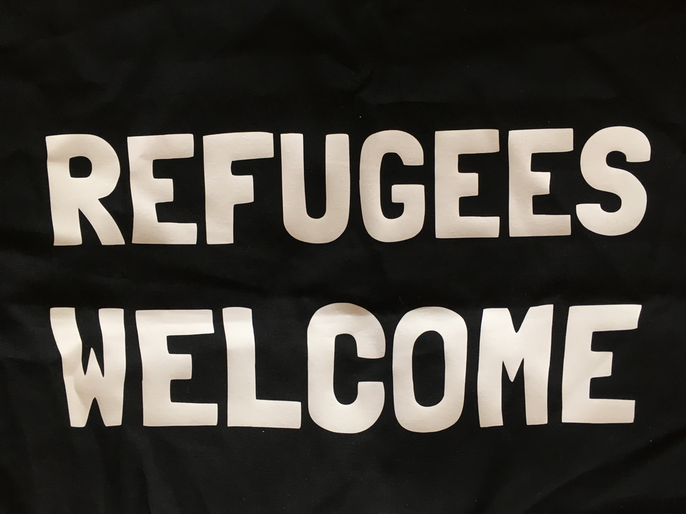 A close up of a tote bag that says refugees welcome