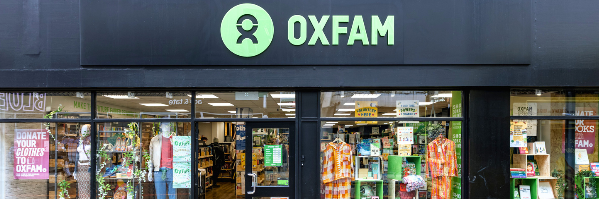 Outside of an Oxfam shop showing the oxfam logo and a colourful window display