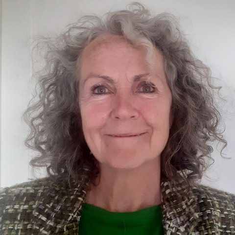 Ruth is white and has grey curly hair. She smiles at the camera.