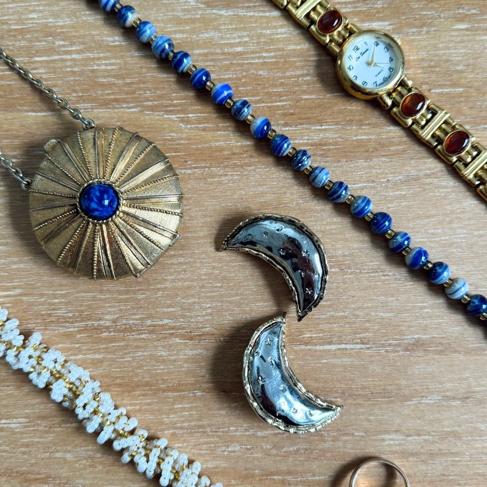second hand jewellery including necklace, bracelet and brooch laid out on a wooden table