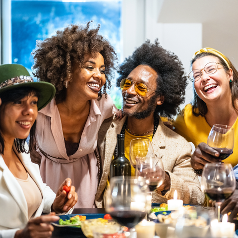 A group of seven people laughing over a table set for a meal