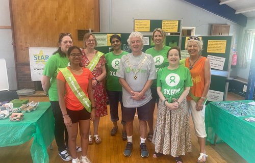 Smiling members of St Alban's Oxfam group in Oxfam t-shirts at a fundraising event.