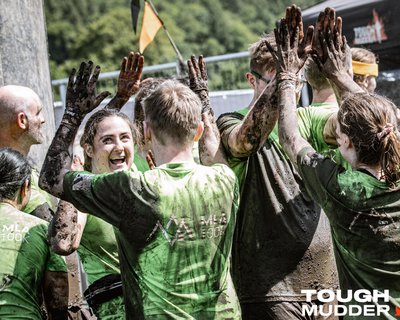 team dressed in green, smiling and high clapping at the end of a race