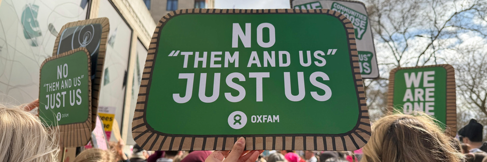 Placard being held above heads, saying "No Them Just Us"