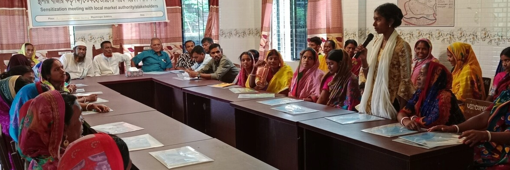 Long tables surrounded with officials and local people in an office style room