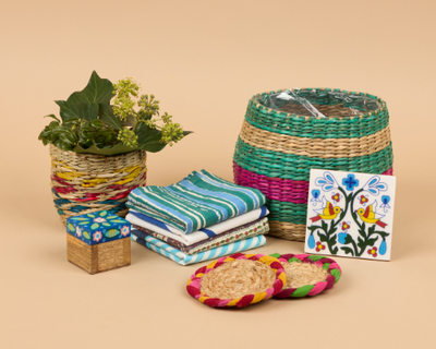 A gift bundle from Sourced by Oxfam, includes a colourful wicker plant pot, coasters, striped napkins and a floral trinket pot.