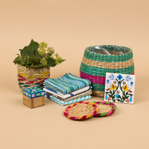 A gift bundle from Sourced by Oxfam, includes a colourful wicker plant pot, coasters, striped napkins and a floral trinket pot.