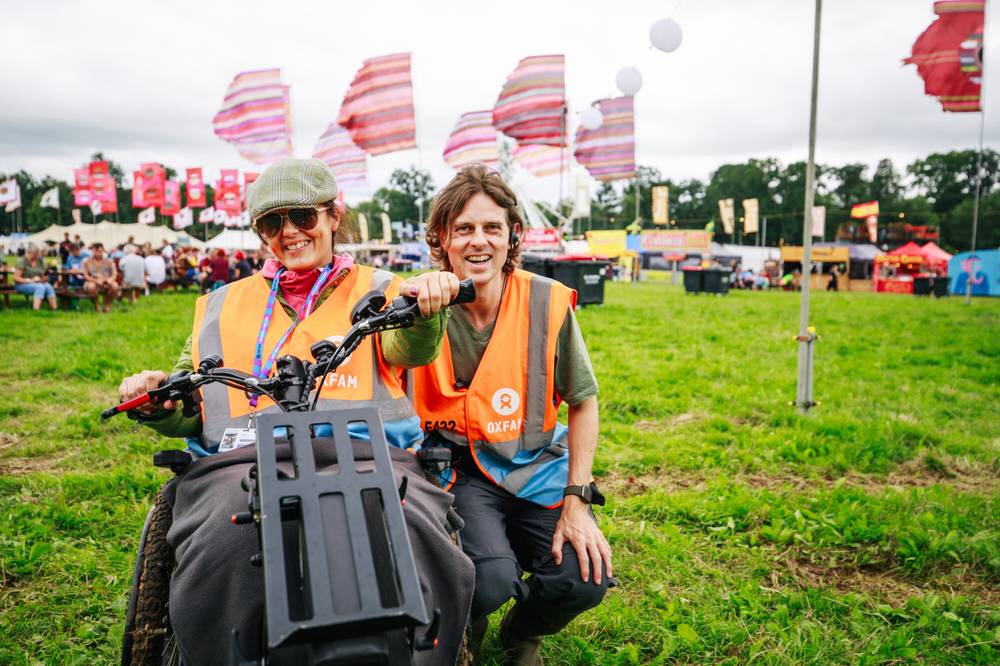 An Oxfam volunteer steward in a wheelchair alongside her PA with food trucks and flags in the background
