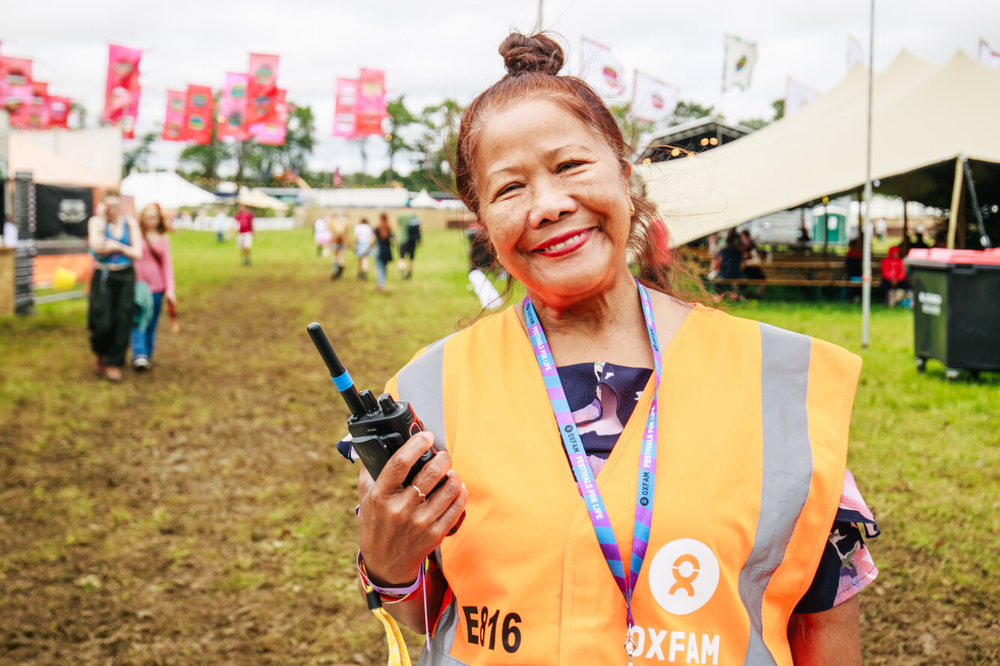 Oxfam festival steward holding a radio and smiling at the camera