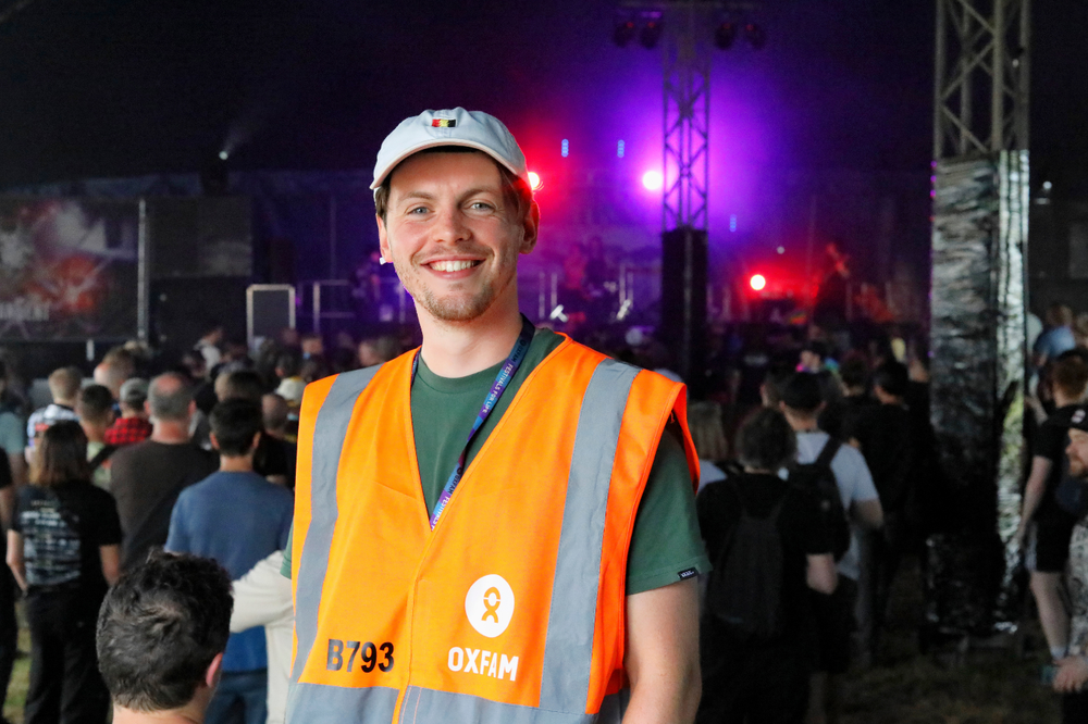 Oxfam festival steward smiling at the camera inside a festival venue