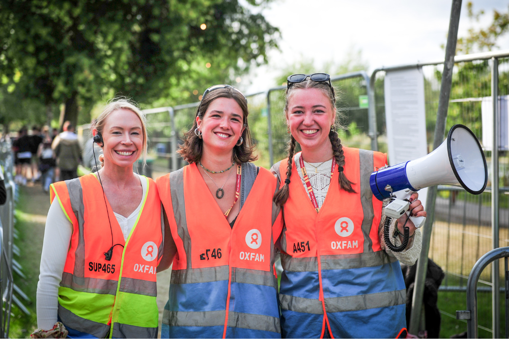 Oxfam volunteer holding a megaphone alongside two other volunteers