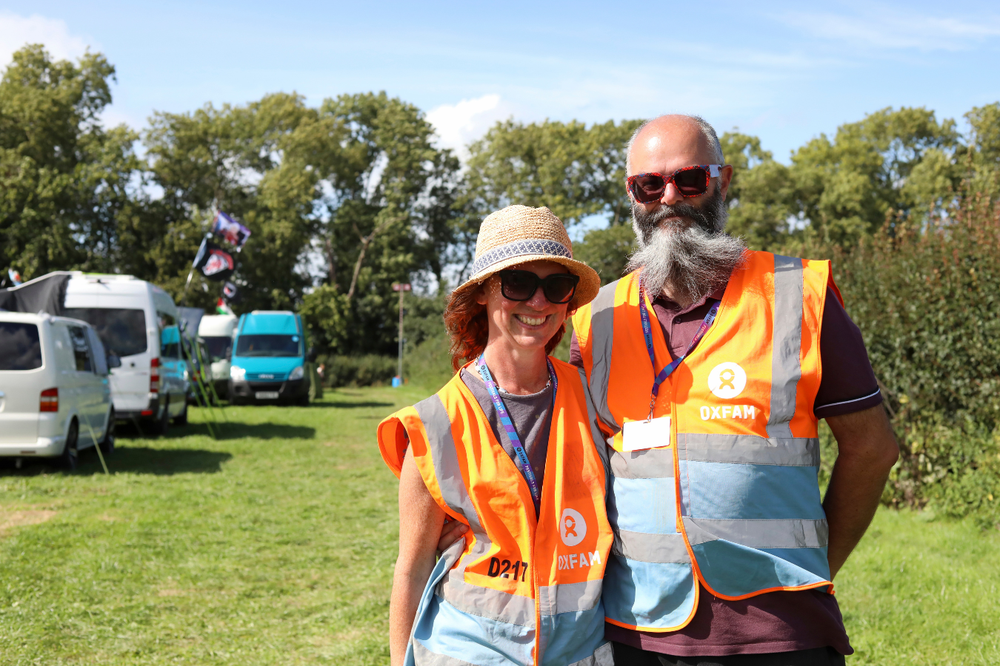 Two Oxfam festival volunteers smiling at the camera while working in a car park