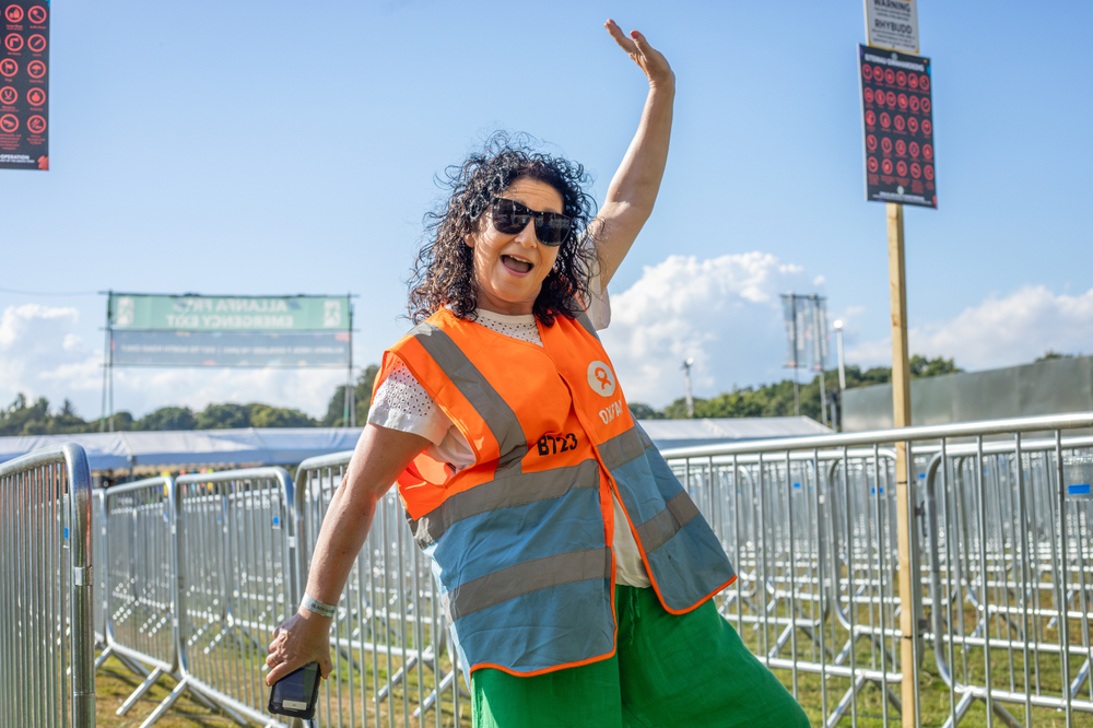 Oxfam festival volunteer working on a gate and smiling with her arms in the air