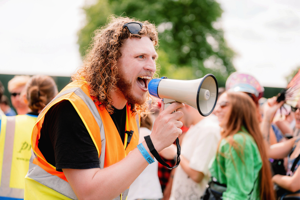 Oxfam volunteer talking into a megaphone at a festival