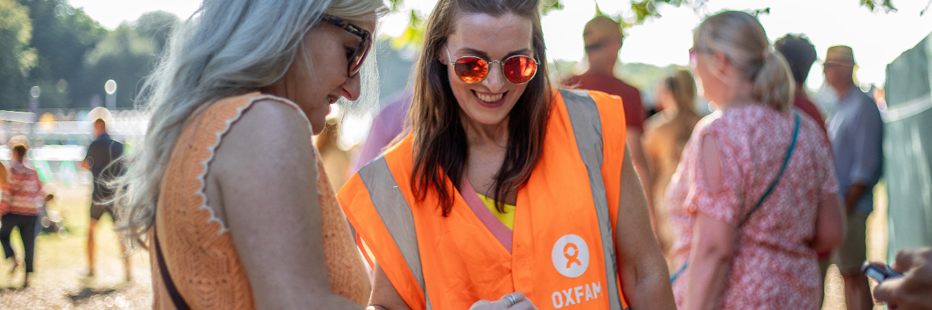 Oxfam festival volunteer scanning a festivalgoers ticket and smiling
