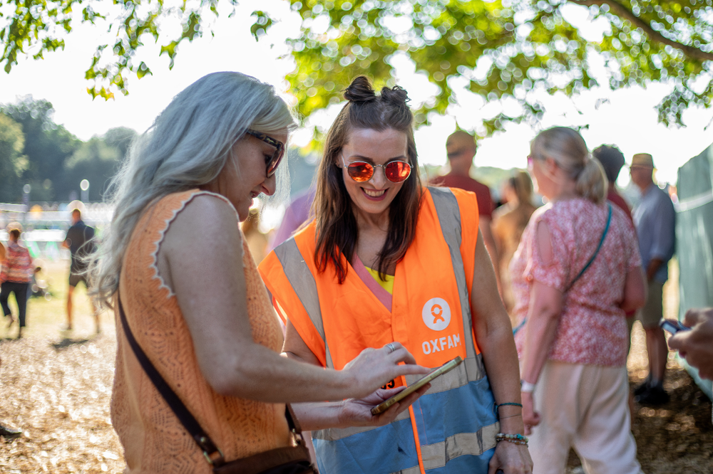 Oxfam festival volunteer scanning a festivalgoers ticket and smiling