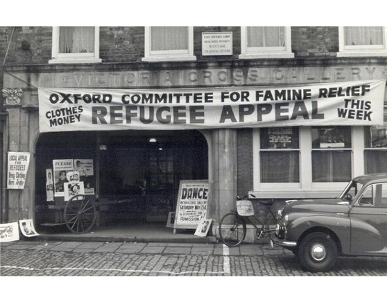 A black and white photo of a building with a banner hanging outside that reads 'Oxfam Committee for Famine Relief refugee appeal'