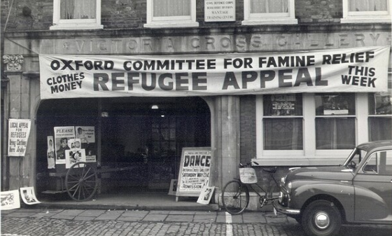 A black and white photo of a building with a banner hanging outside that reads 'Oxfam Committee for Famine Relief refugee appeal'