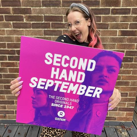 Zara holding an Oxfam Second Hand September sign outdoors