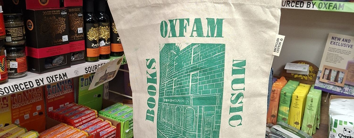 Oxfam volunteer modelling the tote bag inside the Back Wynd shop
