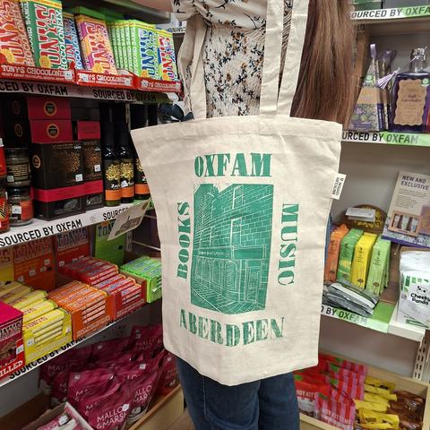 Oxfam volunteer modelling the tote bag inside the Back Wynd shop