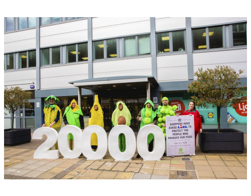 A group of campaigners dresses as fruit holding a bit number '20000' and a placard reading "Shoppers have asked Lidl to protect the people who produce our food".