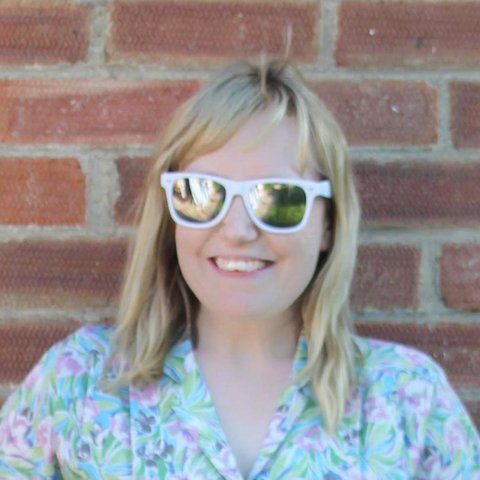 A smiling blonde woman in sunglasses