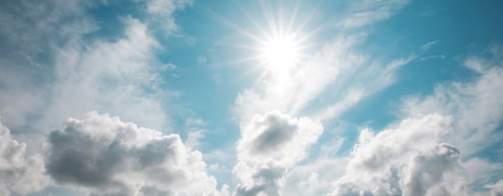 Blue and cloudy sky with sun peaking through