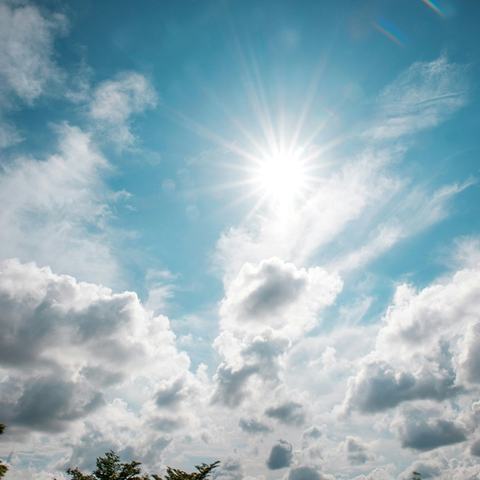 Blue and cloudy sky with sun peaking through