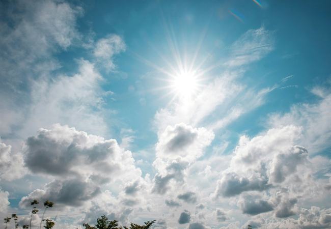 Blue and cloudy sky with sun peaking through