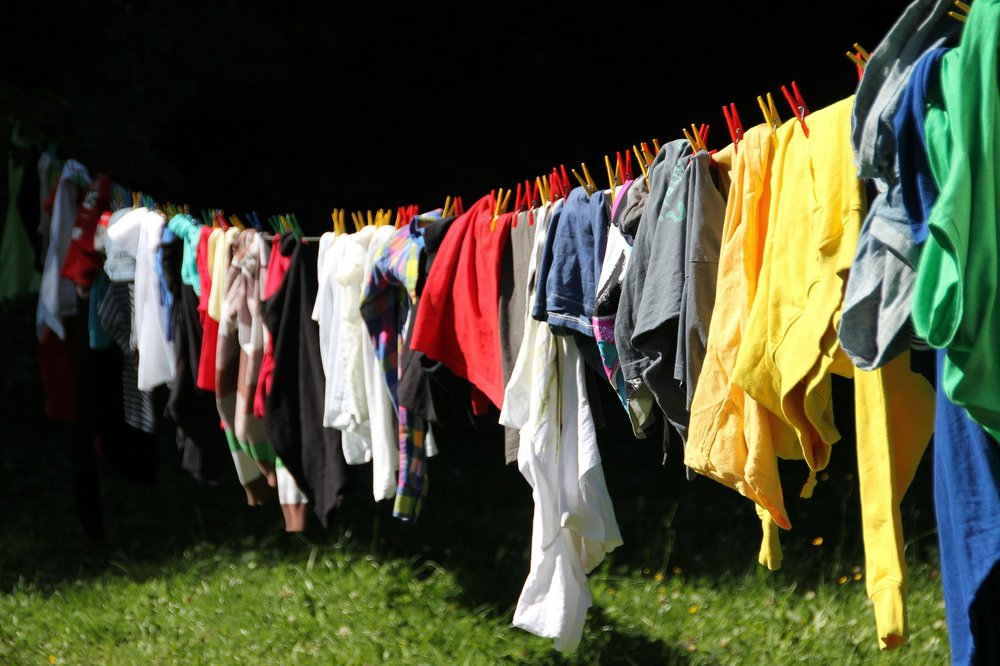 Colourful washing on a washing line above green grass.