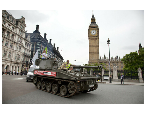 A tank being driven through central London with a banner for Oxfam's Control Arms campaign on the side.