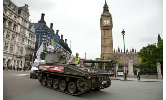 A tank being driven through central London with a banner for Oxfam's Control Arms campaign on the side.