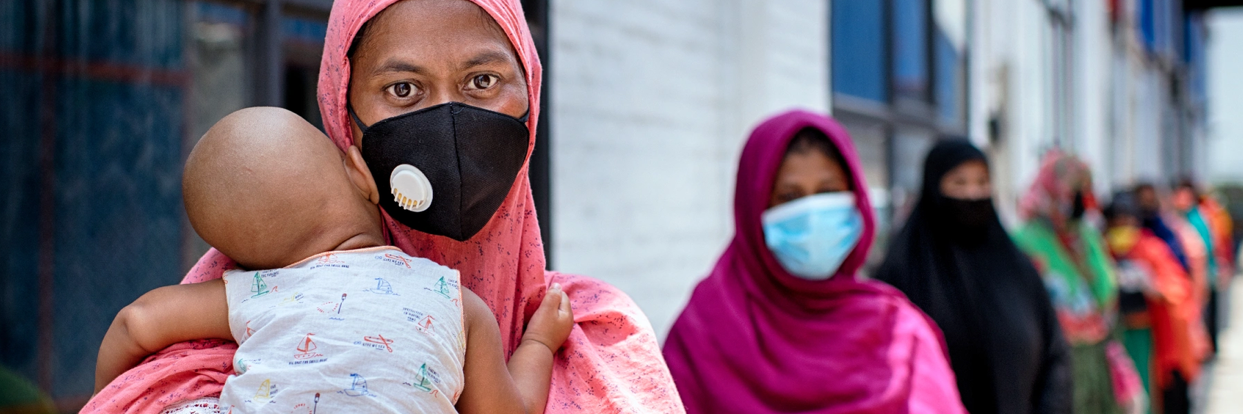 Shahida Akter Lucky stands in line with her child at a food distribution carried out by Oxfam partner Nari Maitree in Bangladesh. Photo: Fabeha Monir / Oxfam