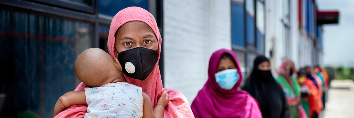 Shahida Akter Lucky stands in line with her child at a food distribution carried out by Oxfam partner Nari Maitree in Bangladesh. Photo: Fabeha Monir / Oxfam