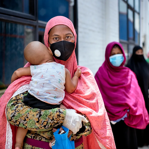 Shahida Akter Lucky stands in line with her child at a food distribution carried out by Oxfam partner Nari Maitree in Bangladesh. Photo: Fabeha Monir / Oxfam