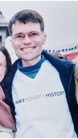 Dominic standing in Trafalgar Square wearing the white Make Poverty History t-shirt.